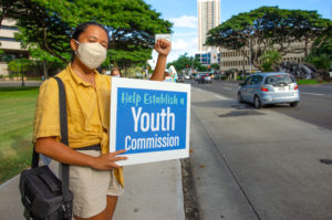Staff writer Kiana Dulan participates in a sign-waving in support of establishing a Hawai'i Youth Commission.